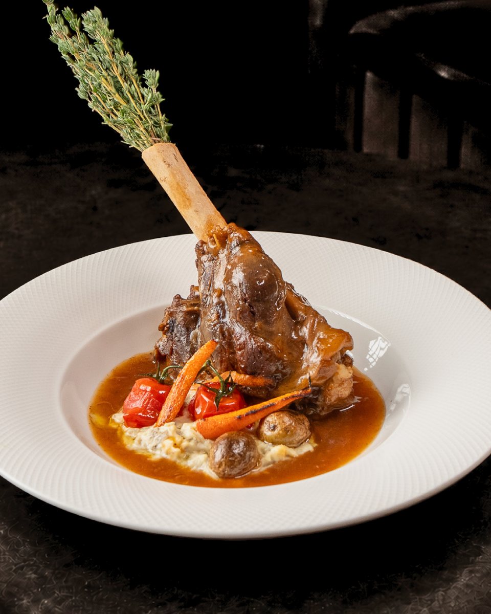 Slow-braised lamb shank on the bone with roasted vegetables and jus